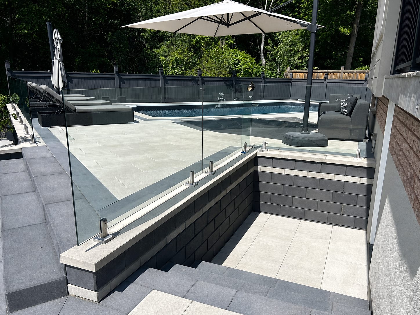 Modern glass-railing pool deck with porcelain pavers
